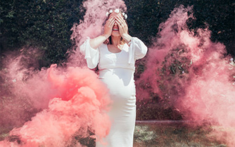 Woman surrounded by pink smoke at gender reveal